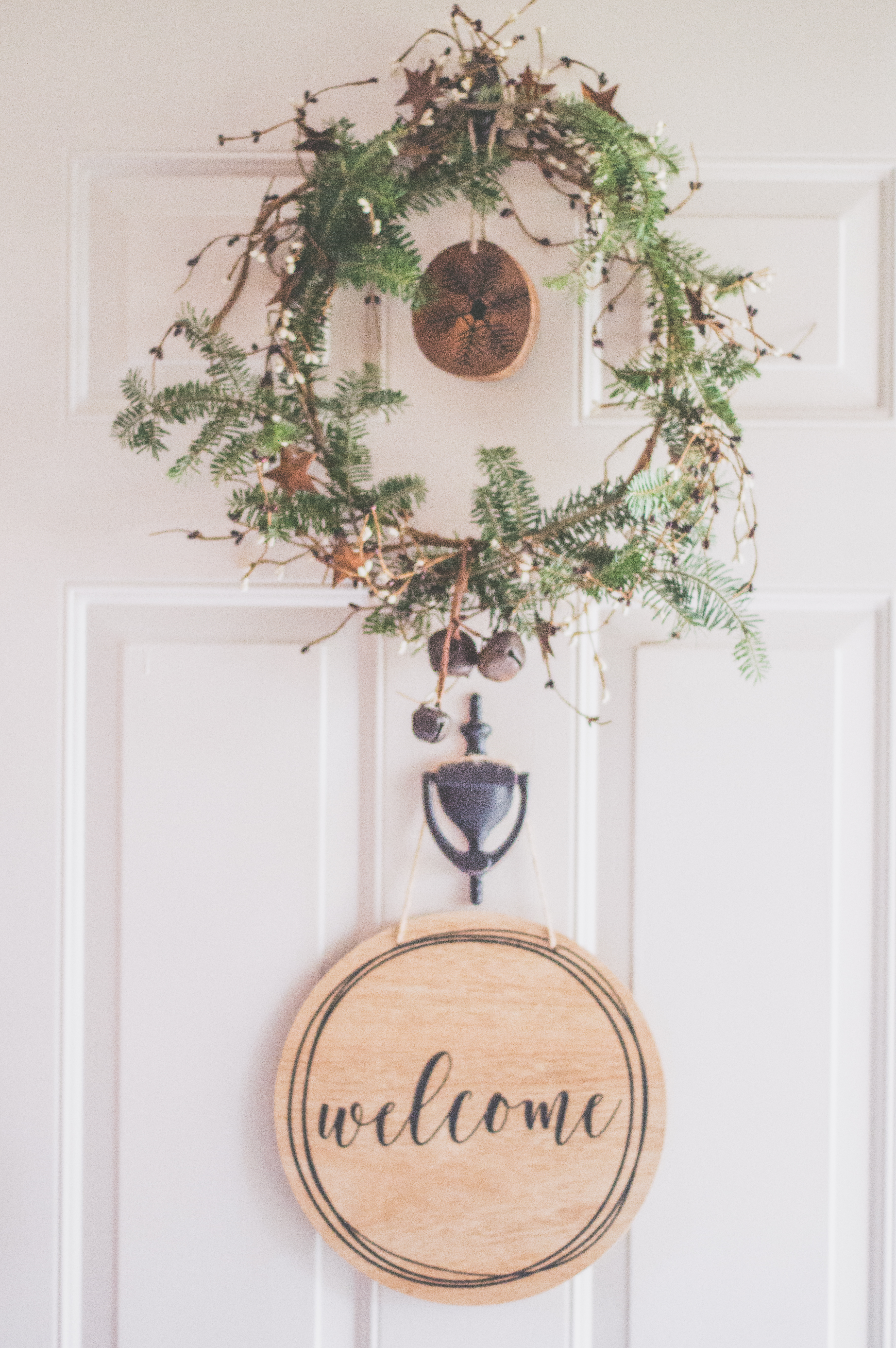 Photo of a white door with a hanging wreath and welcome decor