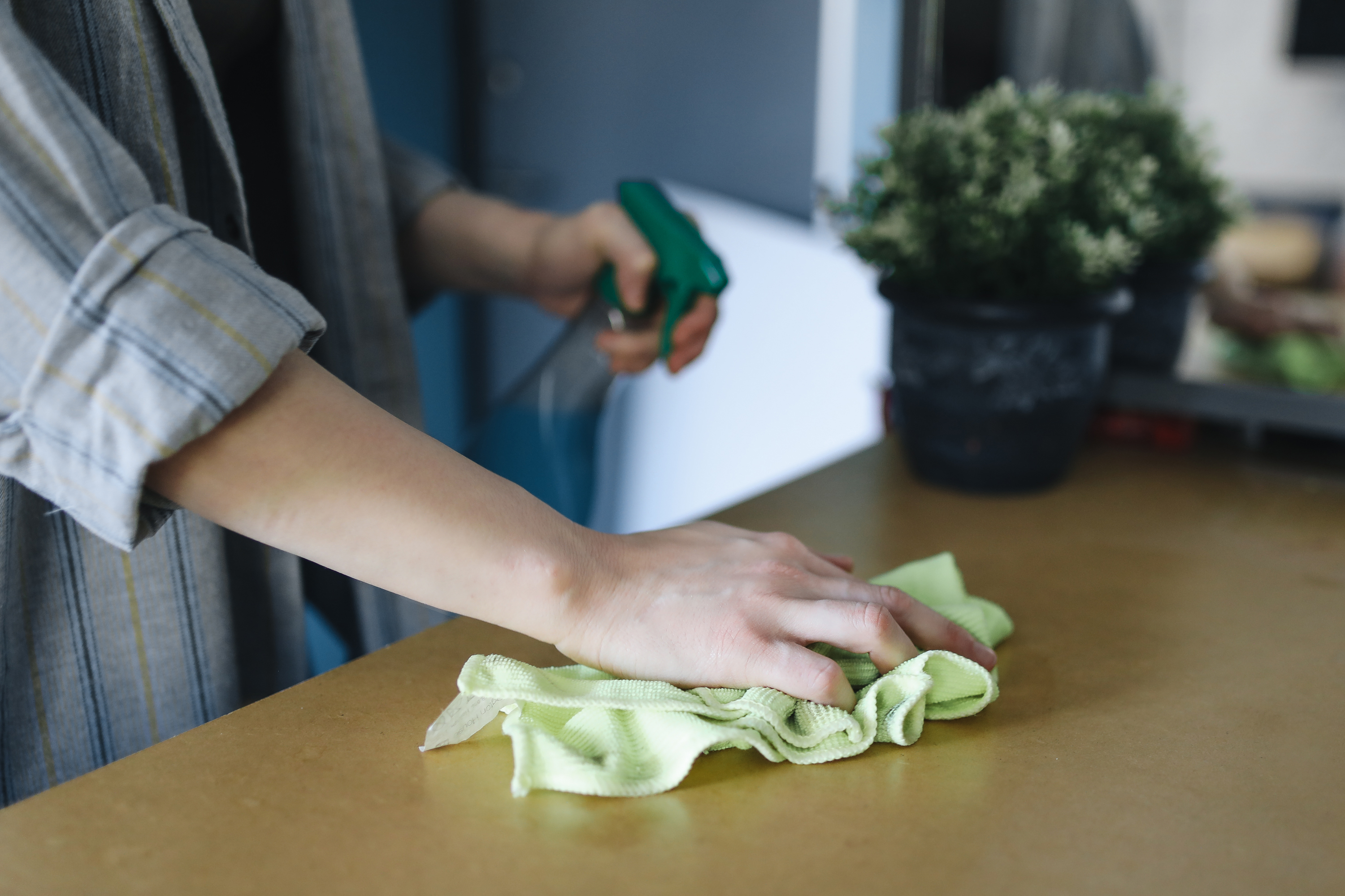 A person cleaning the table with cleaning cloth